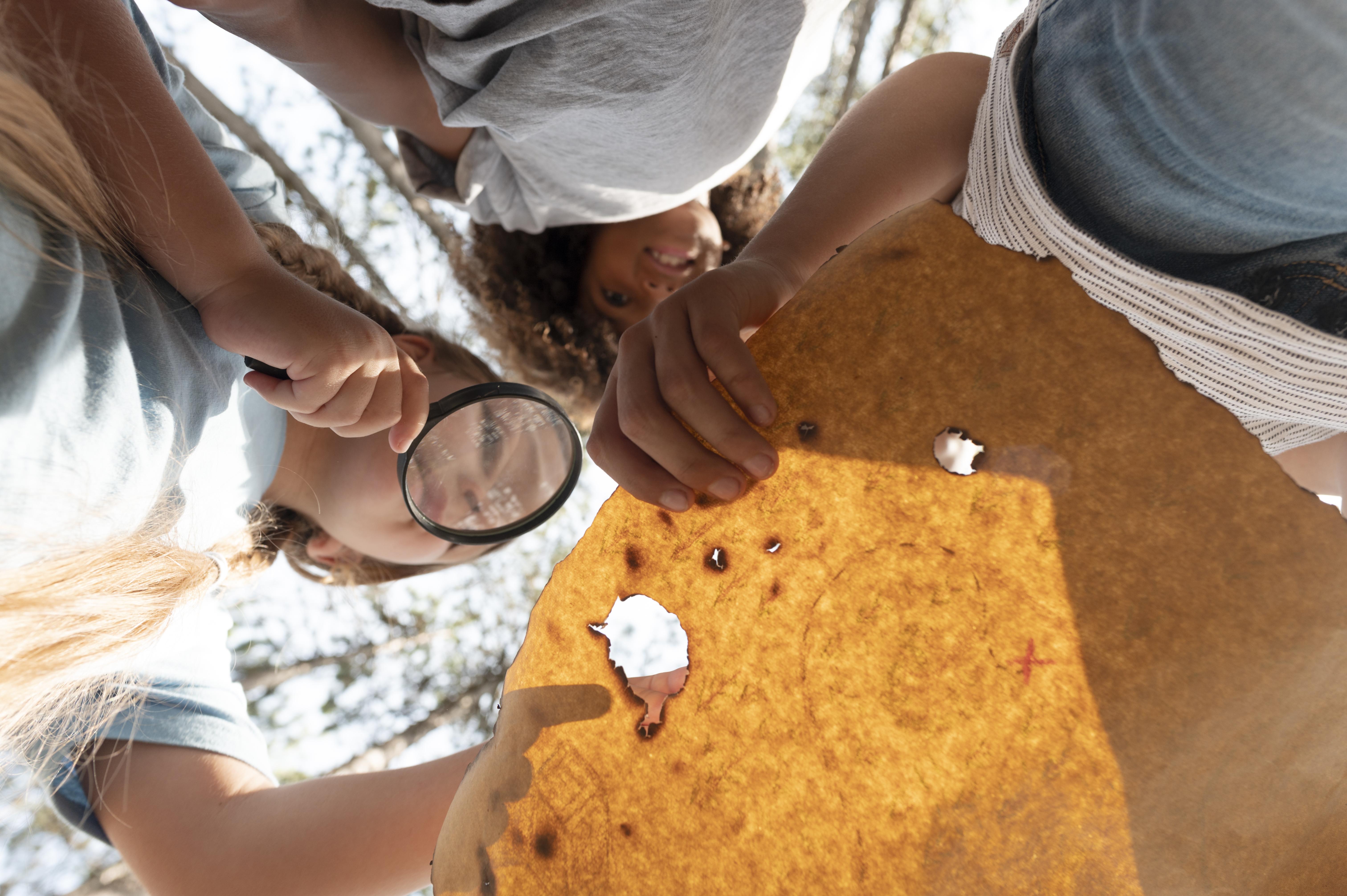 Crianças a explorar com uma lupa, em contacto com a natureza